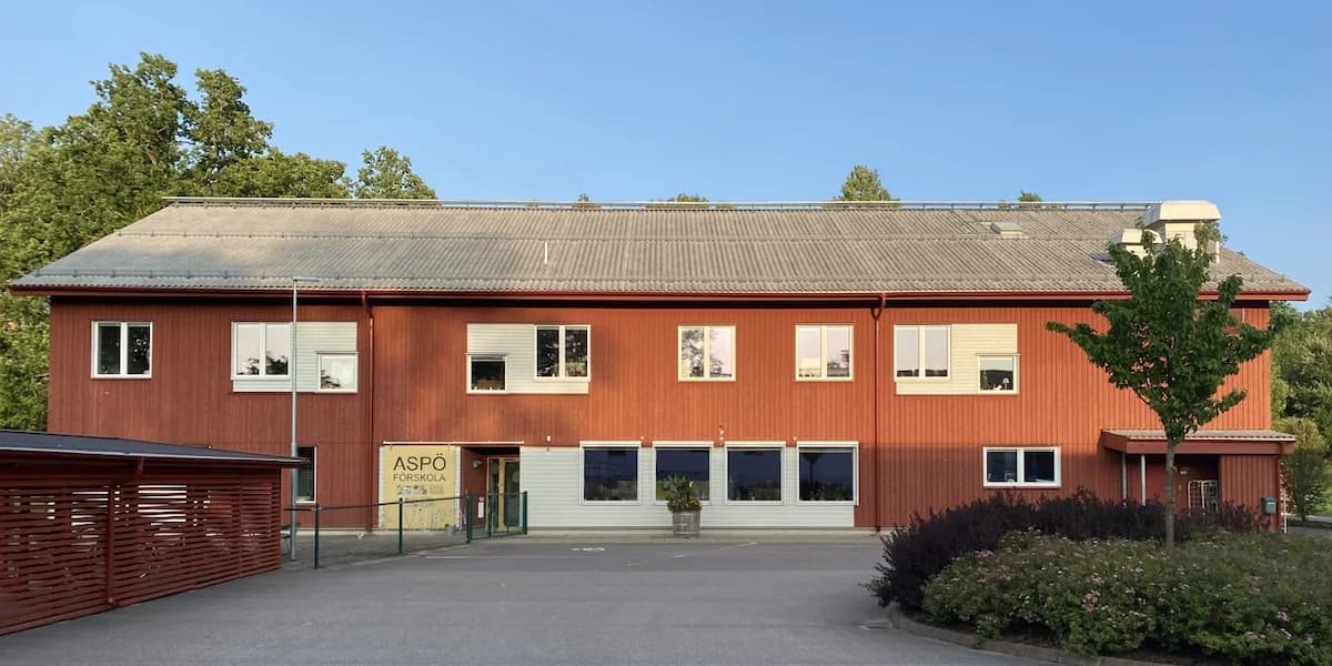 En stor röd byggnad med en parkeringsplats framför sig