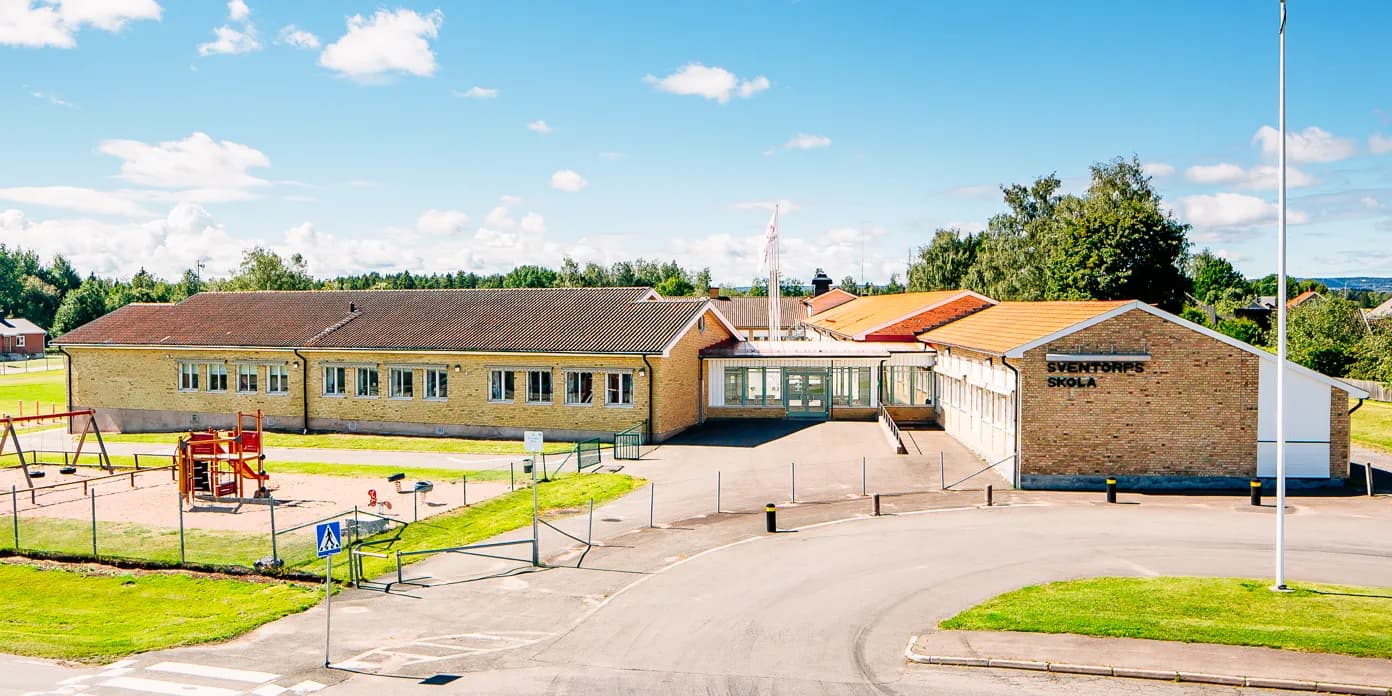 En skolbyggnad med en lekplats framför sig