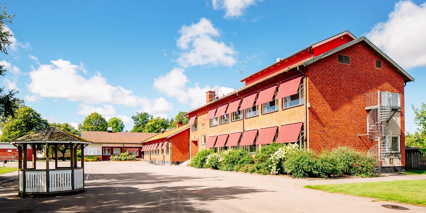 En röd tegelbyggnad med skolgård